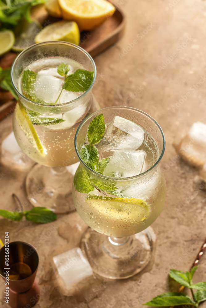Fototapeta premium Mojito long rum drink with fresh mint, lemon juice, ice cubes and soda on brown textured background. Summer party cocktails with text space
