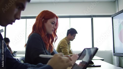 Attentive students in a classroom with tablets and a digital whiteboard.