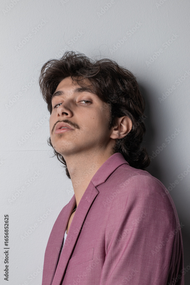 Obraz premium Studio photo of a young man wearing a pink suit. Vertical photo