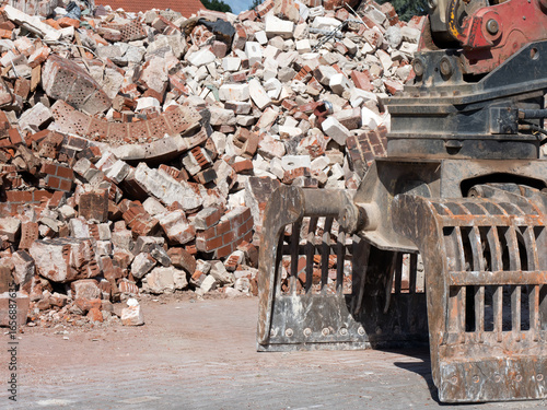 Abbruch- und Sortiergreifer eines Baggers vor Bauschutt von Abbrucharbeiten