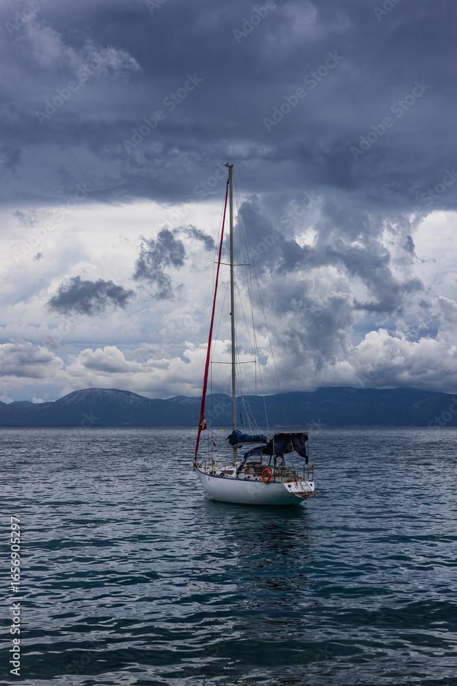 Naklejka premium Sailboat off the coast with dramatic clouds in the background. Adriatic Sea, Croatia
