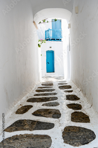 Scenic alleyway with white painted stone walkway and blue  door and railings in Mykonos, Greece