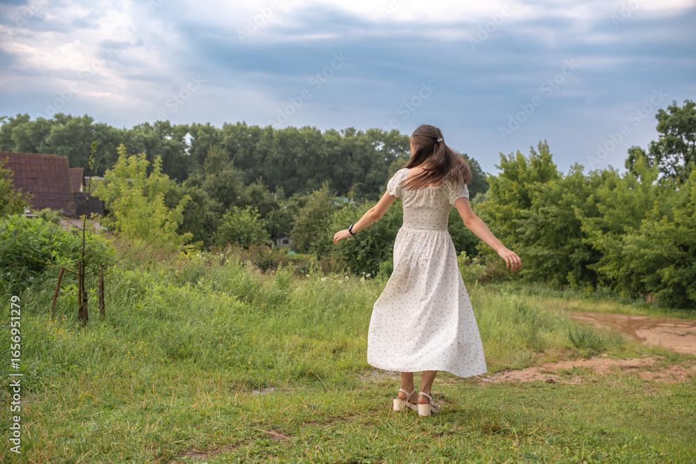 Portrait of a young beautiful dark-haired girl in a summer dress in the park in summer. Portrait of a young beautiful dark-haired girl in a summer dress in the park in summer.