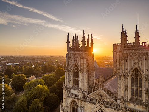 Aerial view of York Minster in York, North Yorkshire, UK, at sunrise, showing the medieval cathedral’s intricate Gothic architecture and surrounding historic cityscape on a summer morning August 2025.