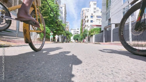 Dhaka, Bangladesh-09-04-2025: Low-Angle View of Two People Cycling on a City Street