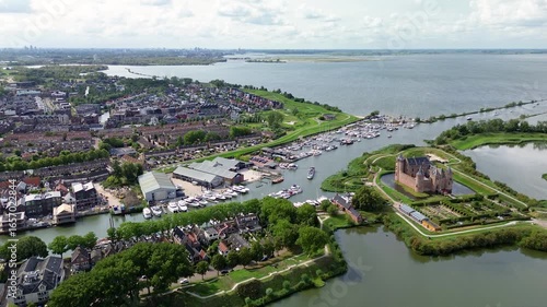 Muiden, North Holland, Netherlands - 09.06.2025: Stunning aerial view of Muiderslot Castle in the Netherlands, surrounded by canals, a marina full of boats, and a charming townscape stretching