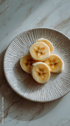 Sliced Bananas Arranged Neatly on a Textured Plate on a Marble Countertop
