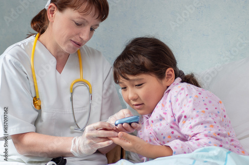 Asian girl at hospital getting her blood sugar measured by doctor or nurse during medical health check-up to prevent diabetes