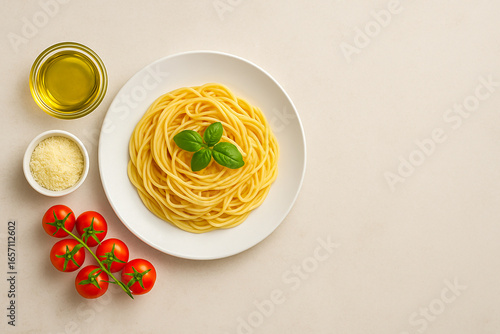 Plate of spaghetti with basil, tomatoes, olive oil, and parmesan on beige background