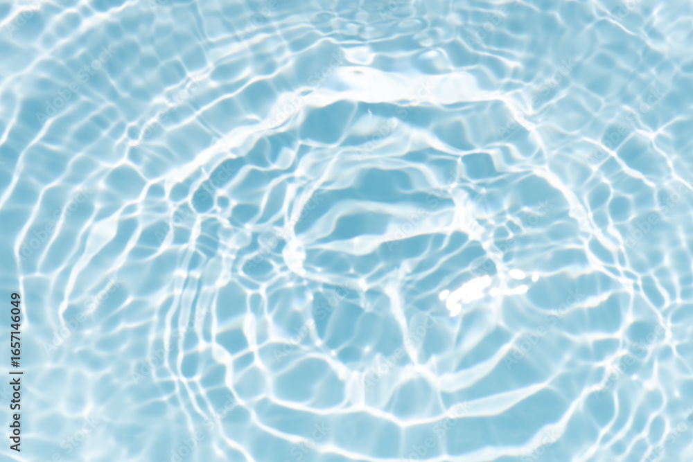 Obraz premium Blue water with ripples on the surface. Defocus blurred transparent blue colored clear calm water surface texture with splashes and bubbles. Water waves with shining pattern texture background.