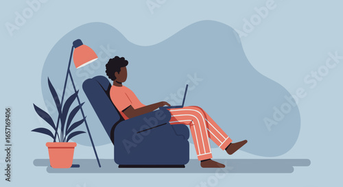 African American man relaxing comfortably in an armchair, working remotely on his laptop at home. Illustrates modern work-life balance and digital connectivity.