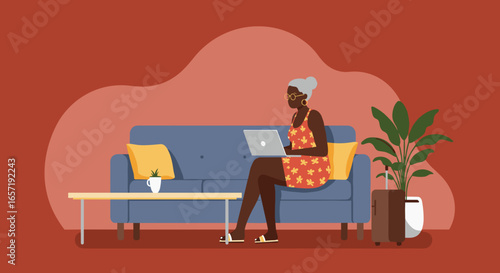 Mature Black woman comfortably using a laptop on a couch at home, embodying remote work, online learning, or travel planning.