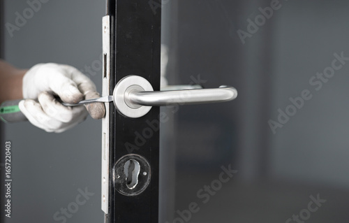 Hands using screwdriver to repair a door lock with a screwdriver
