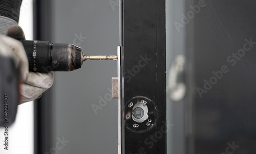 man with screw gun repairing door lock indoors