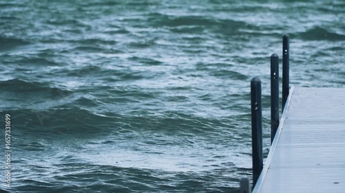 Shot of a white dock extending out into the water on a lake with big, heavy waves