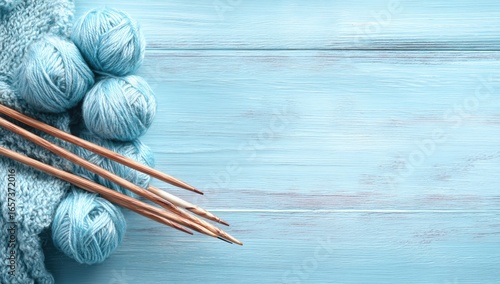 Light blue yarn balls and knitting needles on a light blue wooden background