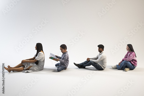 Obraz na płótnie Four people are sitting on a white surface one reading a book.