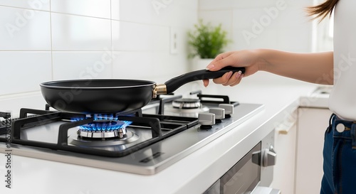 Woman preparing food in a modern kitchen with a frying pan on a gas stove for cooking an elegant