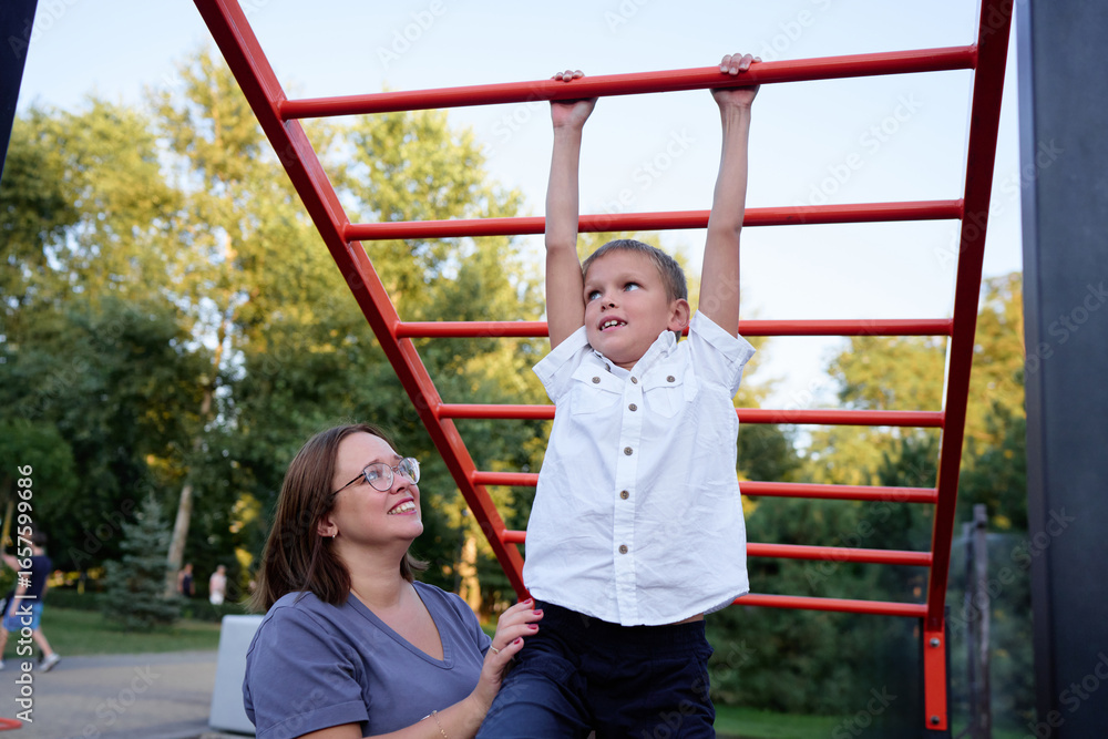 Obraz premium Mother Helping Her Son Learn on Playground Monkey Bars