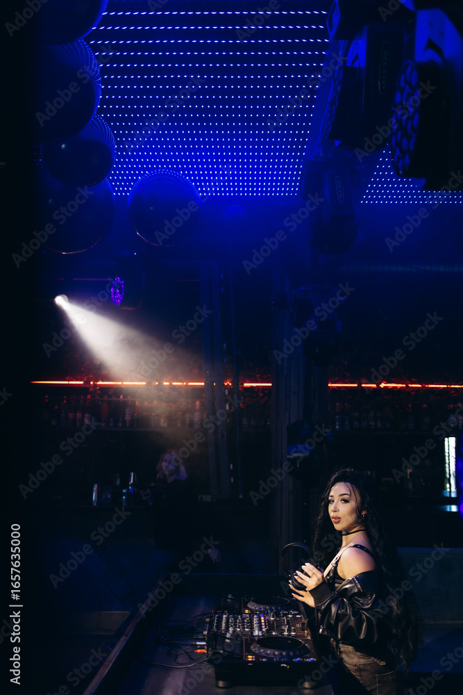 Obraz premium DJ Performing at a Nightclub with Vibrant Lights and Modern Mixing Equipment