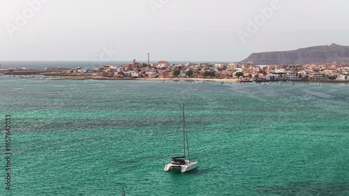 Aerial view of the city of Sal Rei, luxury yacht moored in turquoise ocean,background the port, its old color city and the desert with the mountains