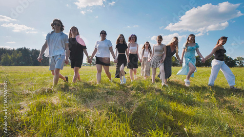 Fotografia High school students happily holding hands and strolling through a sunny field d