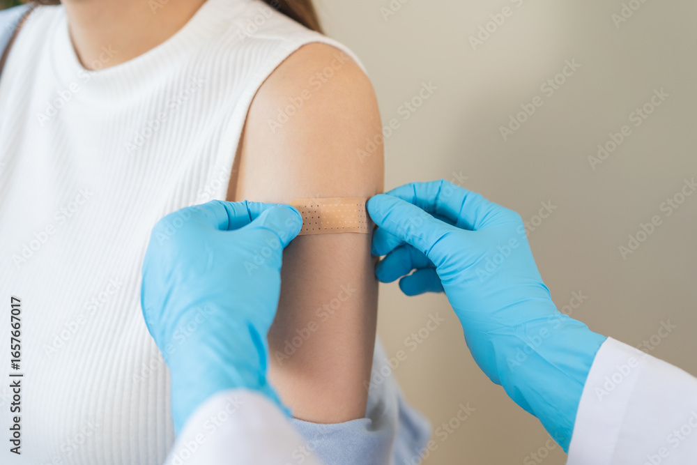 Fototapeta premium Vaccination coronavirus, hand of doctor apply plaster, bandage after doctor giving vaccine, injection dose on arm patient, immunization disease prevention against flu pandemic influenza, health care.