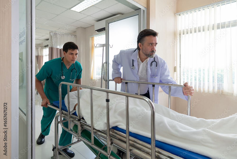 Obraz premium Two healthcare worker are hurriedly transferring a patient on a stretcher in a bright hospital emergency room during the day, illustrating urgency and teamwork in medical care.