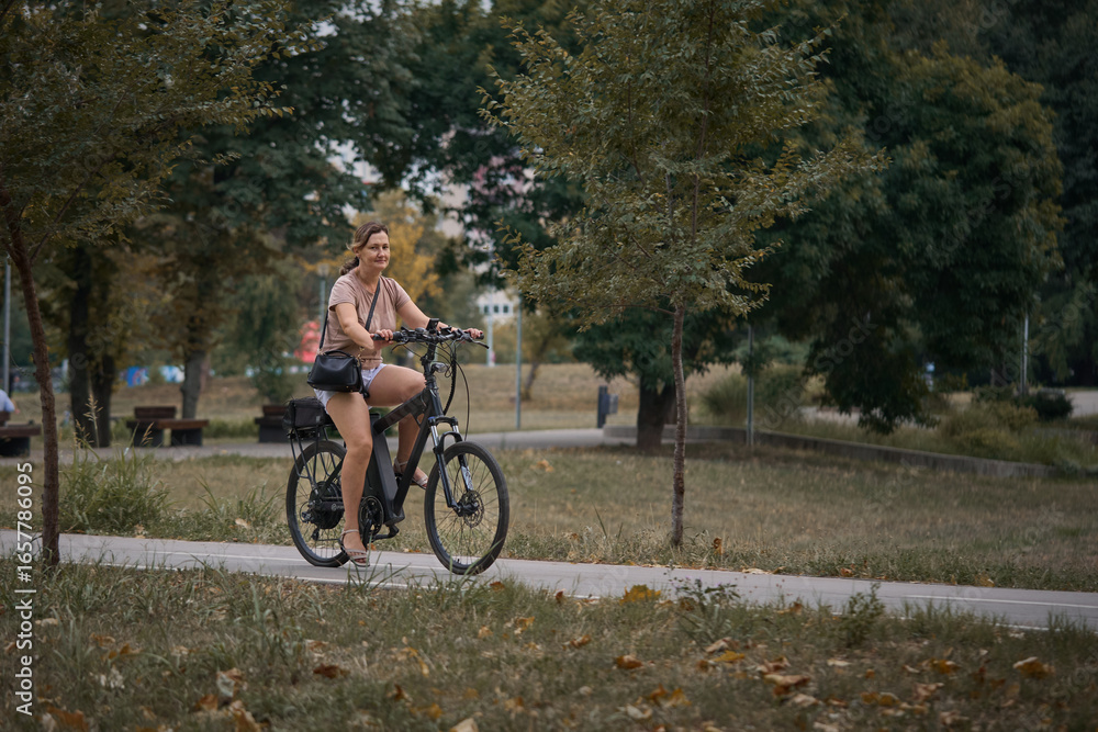 Fototapeta premium Young beautiful woman riding a bicycle in the park. Active people. Outdoors
