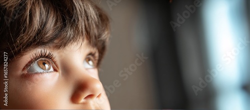 Young boy looking up with curiosity and wonder in indoor setting, kid's pray, orphan