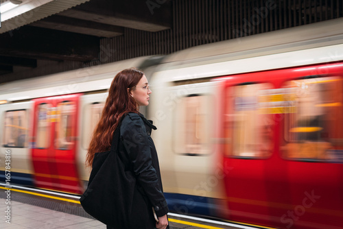 Young woman standing in front of subway at platform