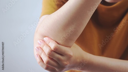 Close-up of a person holding their elbow with both hands, representing elbow pain, joint injury, arthritis, and healthcare concepts for medical and wellness use.