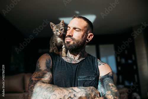 Mixed breed cat sitting on muscular man's shoulder at home