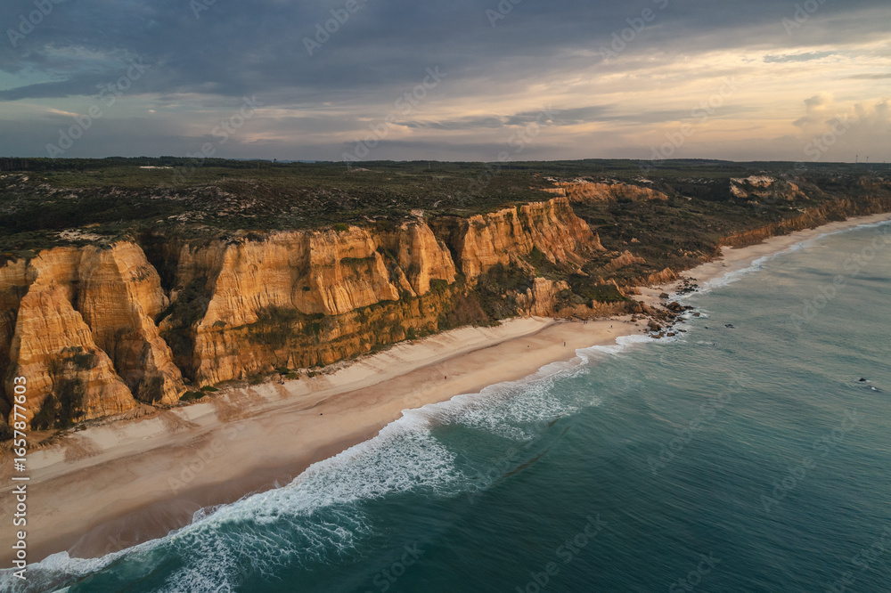 Obraz premium Portugal’s Praia de Vale Furado – wild Atlantic beach with golden cliffs, soft sand and dramatic waves. Perfect for nature lovers, photography, travel and peaceful seaside landscapes.