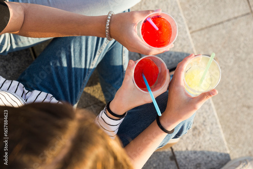 Three young women toasting with soft drinks, partial view