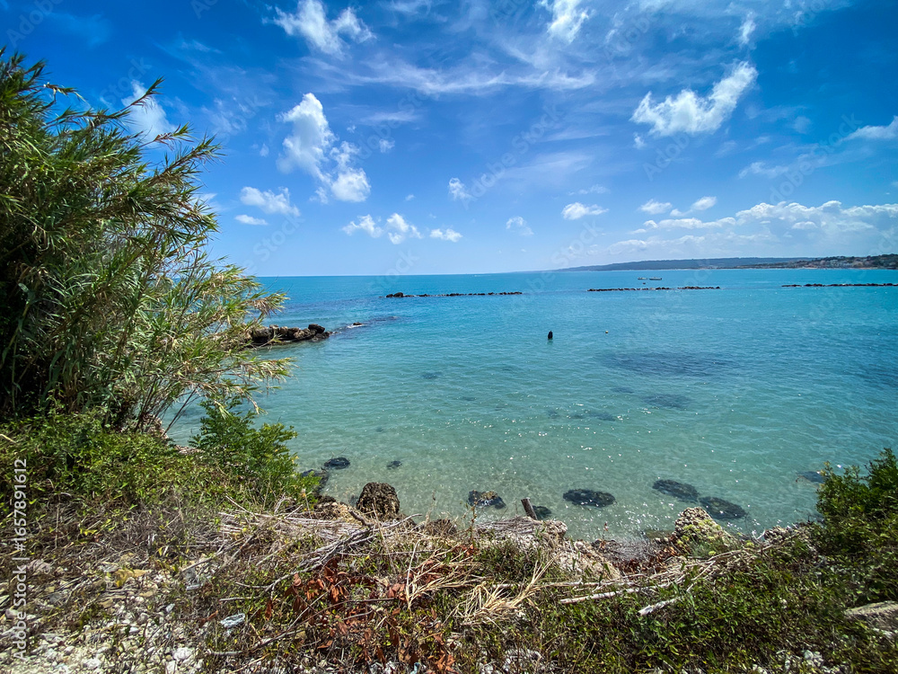 Fototapeta premium Calm turquoise water of the Adriatic Sea with breakwaters and vegetation on a sunny day in Rocca San Giovanni, Abruzzo, Italy