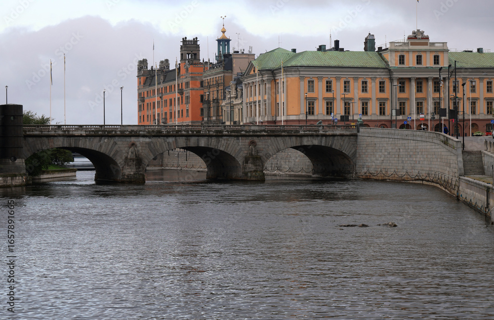 Obraz premium Photo with a view of the Norrbro Bridge across the Norrstrom Canal and the historic buildings on the waterfront at dawn in central Stockholm, Sweden