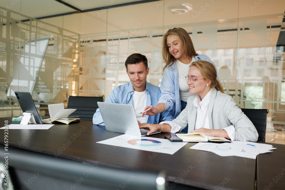 Collaborative professionals brainstorming in a modern office setting with charts and laptops Collaborative professionals brainstorming in a modern office setting with charts and laptops
