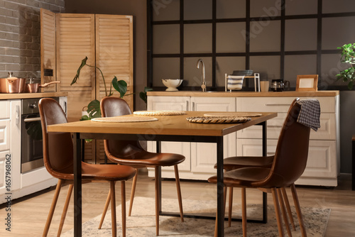 Interior of kitchen with counters, dining table and folding screen in evening