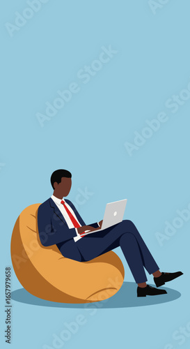 African American businessman in a suit comfortably working on a laptop from a bean bag chair. Represents remote work, modern flexibility, and relaxed productivity.