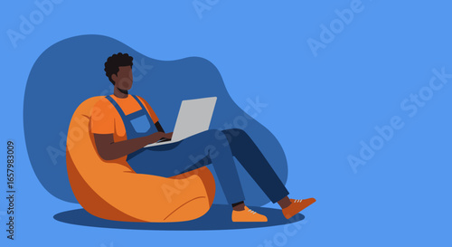 Young person in overalls sits comfortably on a beanbag, using a laptop. Ideal for remote work, online learning, or modern casual lifestyle concepts.