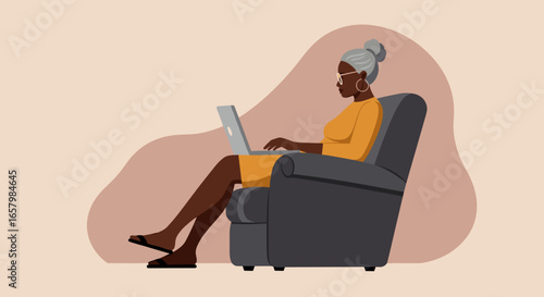 Mature Black woman comfortably working on her laptop in an armchair at home. Represents remote work, online learning, or leisure.