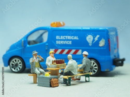 Mini toy of action figure at outdoor with blurred background. Miniature photography concept design. Industrial worker relaxing and resting at workplace.