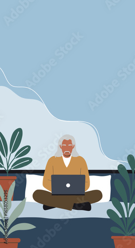 Senior man with long grey hair working on a laptop from home, sitting comfortably on bed amidst plants. Remote work, digital lifestyle.