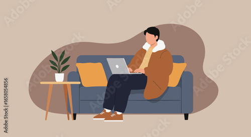 Young man in casual attire working or relaxing on a laptop while sitting comfortably on a sofa in a modern home environment. Ideal for remote work, lifestyle, and technology concepts.