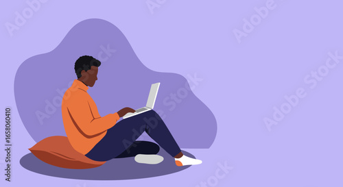 A young person works on a laptop, comfortably seated on a cushion, representing remote work, online learning, or digital lifestyle.