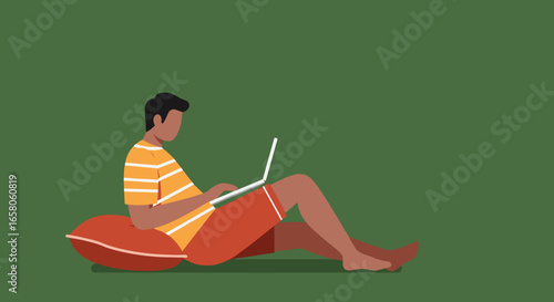Man in casual wear sits comfortably on a cushion, diligently working on his laptop. Depicts remote work, online learning, or modern digital lifestyle.