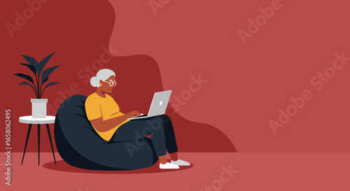 Senior Black woman comfortably uses a laptop on a bean bag chair, highlighting modern senior living, online learning, and remote connectivity.