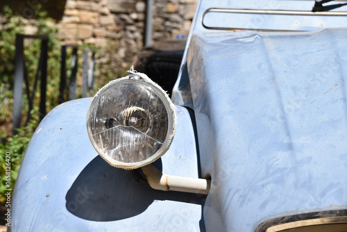 Vintage light blue Citroën 2CV parked near stone wall in a rustic European village, symbolizing retro lifestyle, French culture, and timeless automotive heritage.