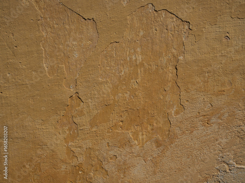 Detailed Texture of a Rough and Cracked Yellow Plastered Wall

